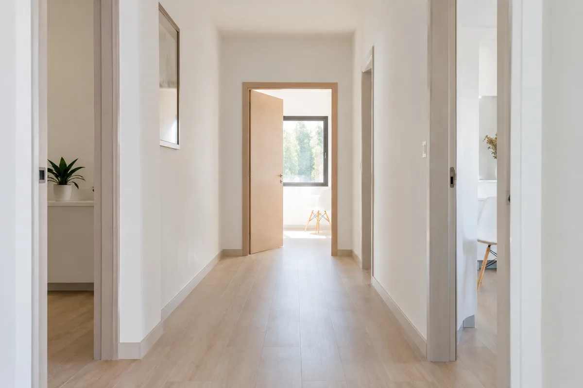 Couloir clair d&rsquo;un cabinet paramédical avec une porte entrouverte sur une pièce vide baignée de lumière